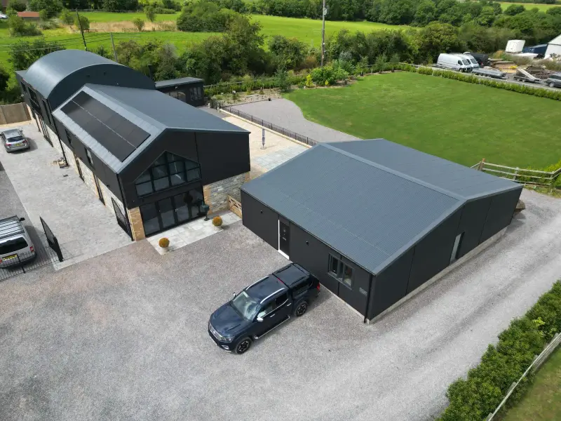 Aerial view of buildings with new dark grey metal roofs and solar panels