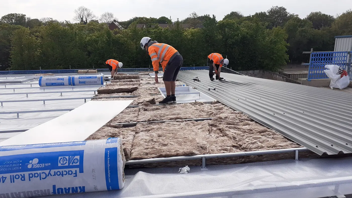 Team laying insulation over the existing roof